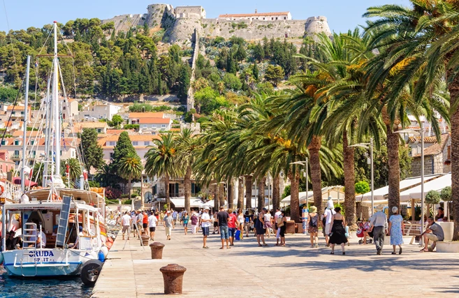 Hvar, Croatia - Tourists stroll in the Riva harbour under the old Spanish fortress