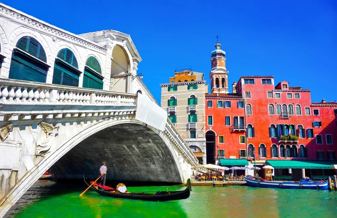 Famous Ponte di Rialto with traditional Gondola under the bridge in Venice